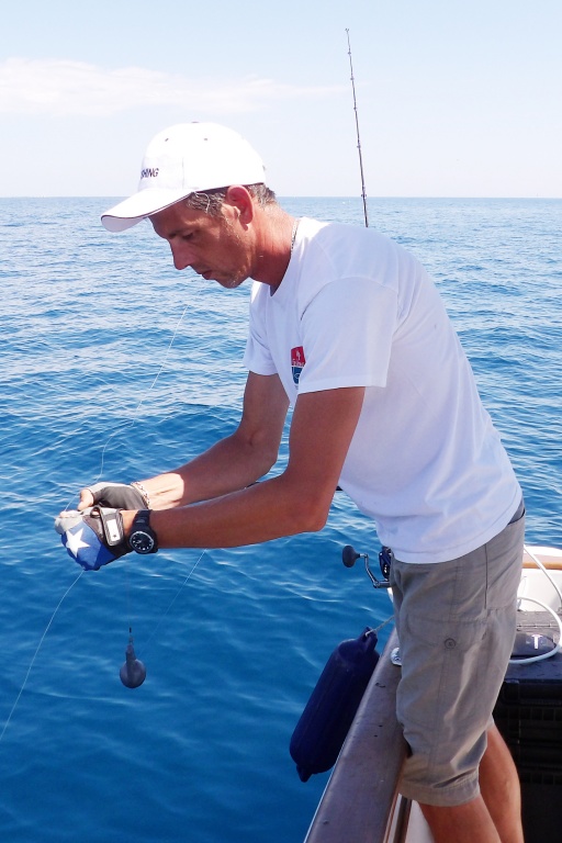 Le moniteur guide de pêche Fabien Harbers en train d’installer le bas de ligne avec vif sur la pince déclencheuse