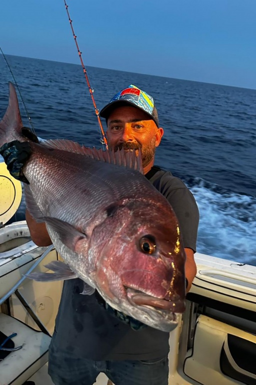 Le pêcheur Jérôme Carlier tenant un gros pagre à bosse aux reflets roses et argentés, pêché au Maroc.
